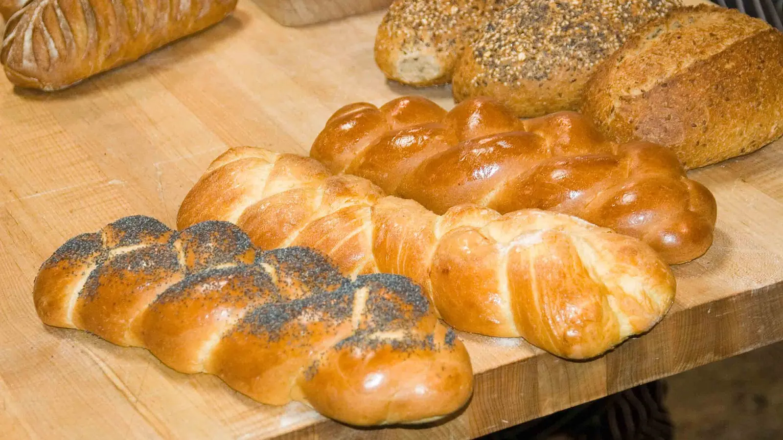 Braided poppy seed loaves and seeded breads on a wooden board
