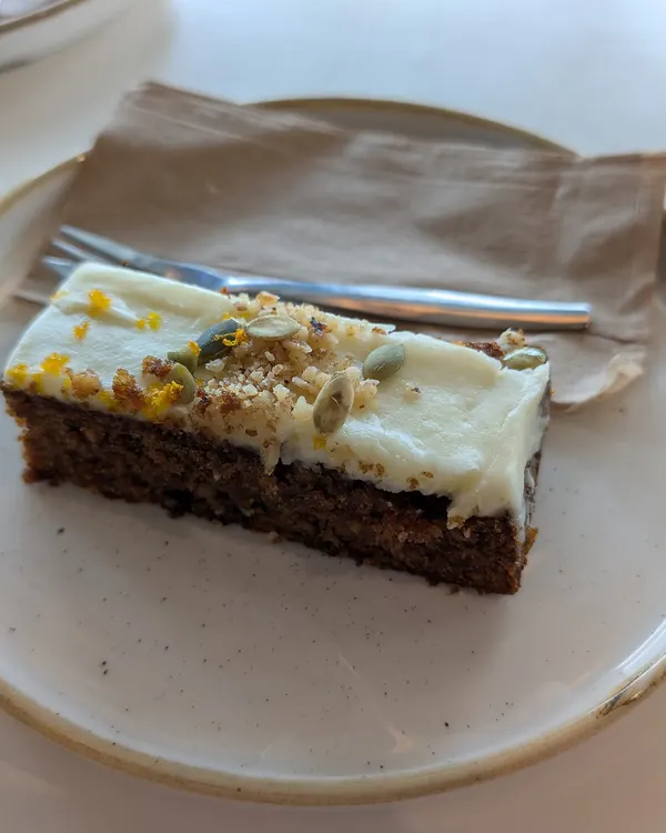 Slice of carrot cake with cream cheese frosting on a plate