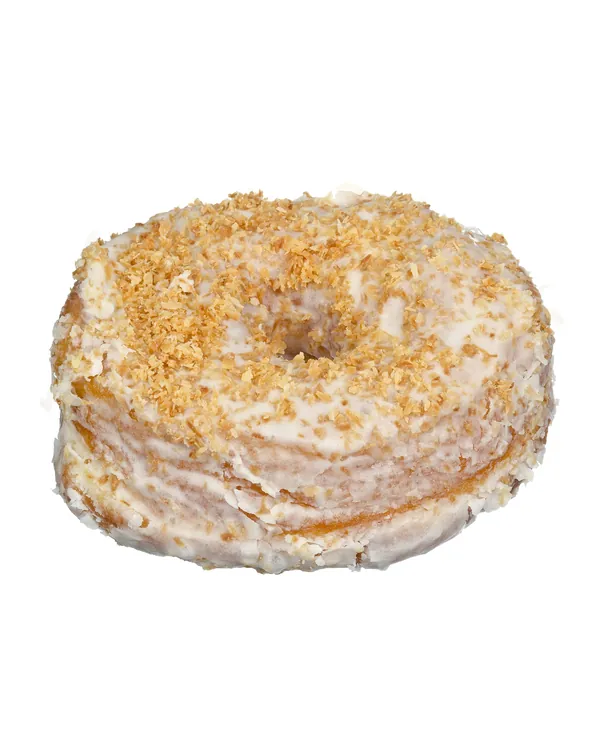Glazed doughnut covered in toasted coconut, on white