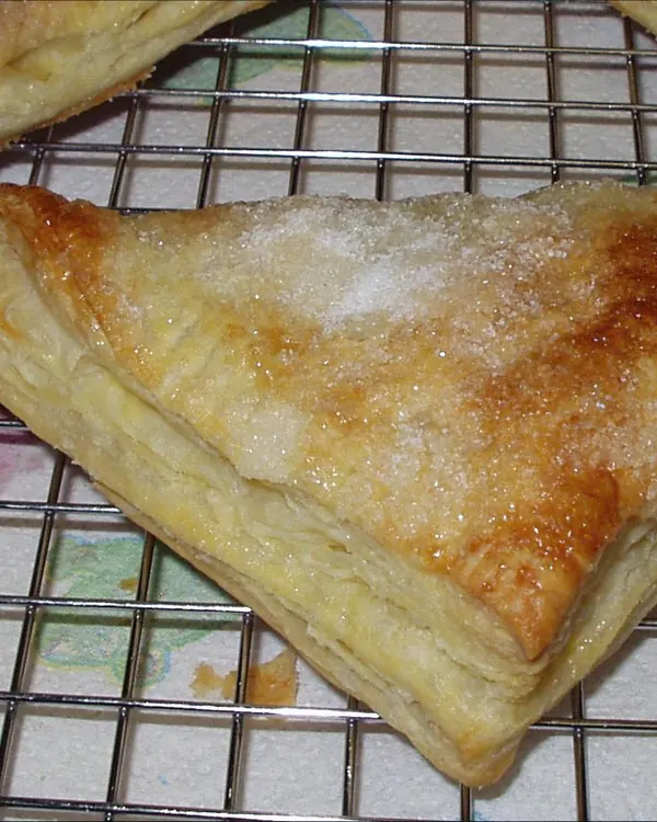 Triangular fruit turnover with coarse sugar on a wire rack